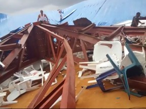 In this image made from video taken on Saturday, Dec. 10, local people survey the scene after a church roof collapsed in Uyo, Nigeria. Metal girders and the roof of a crowded church collapsed onto worshippers in southern Nigeria, killing at least 160 people with the toll likely to rise, a hospital director said Sunday.