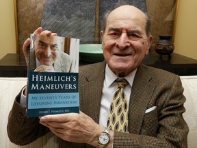 In this Wednesday, Feb. 5, 2014 photo, Dr. Henry Heimlich holds his memoirs prior to being interviewed at his home in Cincinnati. Heimlich is known for developing the Heimlich maneuver that has been used to clear obstructions from the windpipes of choking victims around the world for four decades.