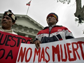 Members of Peru's Achuar ethnic group protest  against oil companies before the Congress in Lima, 19 June 2007. The banner on the right reads "No more deaths".