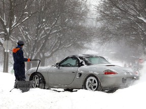 A man shovels out a car in Toronto following a snowfall in 2014