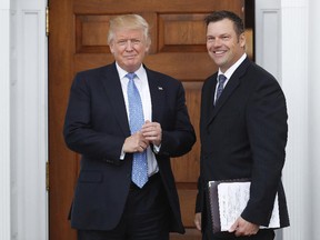 In this Nov. 20, 2016 photo, President-elect Donald Trump pauses for photographs as he greets Kansas Secretary of State, Kris Kobach