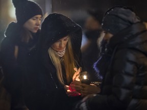 Women try to light a candle to place with flowers in front of the Alexandrov Ensemble building in Moscow, Russia, Monday, Dec. 26, 2016, the day after a plane carrying 64 members of the Alexandrov Ensemble crashed into the Black Sea minutes after taking off from the resort city of Sochi.