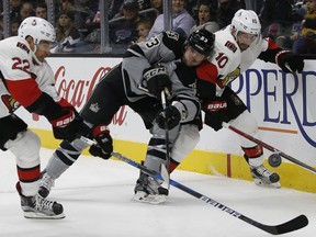 Kings defenceman Kevin Gravel gets his stick on the puck between Ottawa Senators' Chris Kelly, left, and Tom Pyatt during the first period of their game in Los Angeles on Saturday.