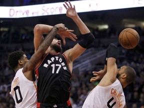 Toronto Raptors'  Jonas Valanciunas loses control of the ball against the double team of Marquise Chriss, left, and Tryon Chander of the Phoenix Suns during NBA action Thursday in Phoenix. The Suns were 93-91 winners.