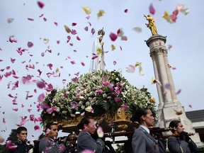 In this Wednesday, May 13, 2015 file photo, worshipper throw flower petals at the statue of the Our Lady of Fatima as it is carried at the Our Lady of Fatima shrine, in Fatima, central Portugal. The centennial of the miracle will be observed in 2017 with a visit by the pope, and it’s one reason that Portugal has turned up on several lists for where to go in the new year.