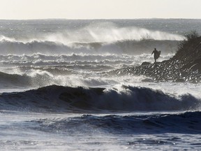 A surfer walks along the shore in Cow Bay, N.S. in a file photo. Canada already has a lot to offer travellers, but as the country celebrates its 150th birthday in 2017 with a year full of sesquicentennial celebrations, there's even more to see and do.