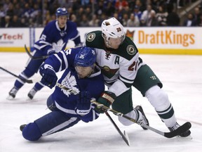 James van Riemsdyk of the Maple Leafs is checked by Minnesota Wild defenceman Gary Suter during their game Wednesday night at the Air Canada Centre in Toronto.