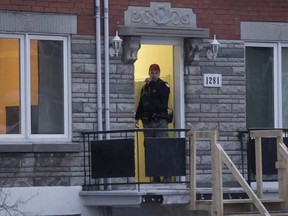 A Montreal police officer stands outside house in Pointe-aux-Trembles Dec. 5, 2016. The shooting of a man there is linked to another shooting and carjacking.