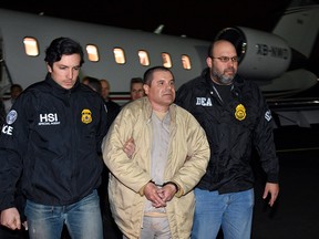 In this photo provided U.S. law enforcement, authorities escort Joaquin "El Chapo" Guzman, center, from a plane to a waiting caravan of SUVs at Long Island MacArthur Airport on Thursday, Jan. 19, 2017, in Ronkonkoma, N.Y. The infamous drug kingpin who twice escaped from maximum-security prisons in Mexico was extradited at the request of the U.S. to face drug trafficking and other charges, and landed in New York late Thursday, a federal law enforcement official said.