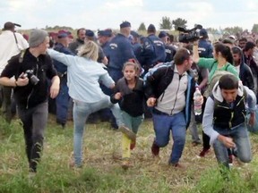 This video grab made on Sept. 9, 2015 shows a Hungarian TV camerawoman kicking a child as she run with other migrants from a police line during disturbances at Roszke, southern Hungary.