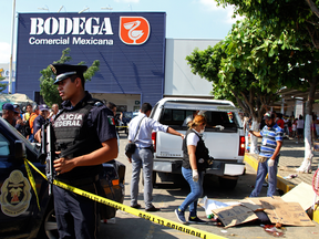 Police and forensics secure the area where six people lie dead, two of them covered with cardboard at right, in Acapulco, Mexico, Wednesday, Jan. 4, 2017.