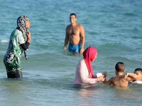 This file photo taken on August 16, 2016 shows fully covered Tunisian Muslim women swimming at Ghar El Melh beach near Bizerte, north-east of the capital Tunis. 
The debate launched this summer in France over the Burkini is not causing such a stir in North Africa where the Islamic swimsuit is uncontroversial as the dress-code on the beaches has become increasingly prudish.