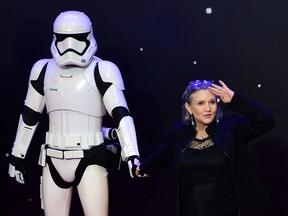 This file photo taken on December 16, 2015 shows US actress Carrie Fisher (R) posing with a storm trooper as she attends the opening of the European Premiere of "Star Wars: The Force Awakens" in central London.