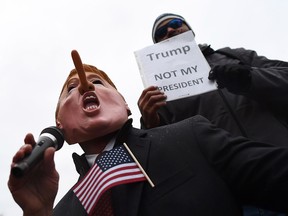 Demonstrators protest against US President-elect Donald Trump before his inauguration on January 20, 2017, in Washington, DC.  Donald Trump will be sworn in as the 45th president of the United States Friday -- capping his improbable journey to the White House and beginning a four-year term that promises to shake up Washington and the world.