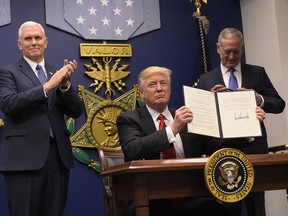US President Donald Trump shows his signature on executive orders alongside US Defence Secretary James Mattis and US Vice President Mike Pence on January 27, 2016 at the Pentagon