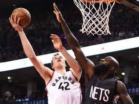 Jakob Poeltl, left, of the Toronto Raptors, goes high to the basket to score past Brooklyn Nets' defender Quincy Acy during NBA action Friday night at the Air Canada Centre. After a slow start, the Raptors were easy 132-113 winners.