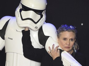 In this Dec. 16, 2015, file photo, Carrie Fisher, right, poses for photographers with a stormtrooper at the European premiere of the film Star Wars: The Force Awakens in London. Fisher died at the age of 60 on Tuesday, Dec. 27, 2016.