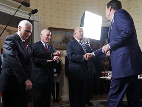 Vice President Mike Pence, left, and Secret Service Director Joseph Clancy stand as President Donald Trump shakes hands with FBI Director James Comey during a reception for inaugural law enforcement officers on Sunday, Jan. 22, 2017 in Washington.