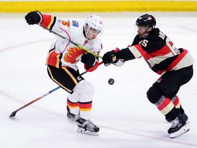 Johnny Gautreau, left, of the Calgary Flames, battles with Ottawa Senators defenceman Erik Karlsson on Jan. 24.