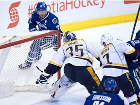 Vancouver Canucks' Henrik Sedin, top left, of Sweden, scores against Nashville Predators' goalie Pekka Rinne, of Finland, during the third period of an NHL hockey game in Vancouver, B.C., on Tuesday January 17, 2017.