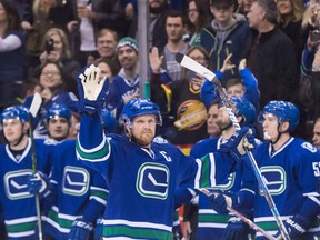 Vancouver Canucks' Henrik Sedin, of Sweden, waves as he receives a standing ovation from his teammates on the bench and the crowd after scoring a goal against the Florida Panthers to record his 1,000th career point, during the second period in Vancouver, on Friday.