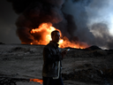 A man stands next to an oil field set on fire by retreating ISIL fighters in Qayyarah, Iraq.