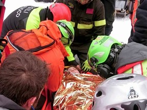 A woman gets assistance after being pulled out from the hotel that was hit by an avalanche on Wednesday, in Rigopiano, central Italy, Friday, Jan. 20, 2017