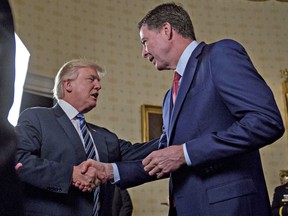 U.S. President Donald Trump shakes hands with FBI Director James Comey, during a reception in the White House on January 22, 2017