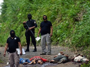 Police and forensics officers inspect a crime scene where four alleged gang members of the Mara Salvatrucha gang were killed 30 km east of San Salvador on October 21, 2015.