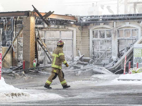 A Laval firefighter surveys the scene of a fire that destroyed several businesses at René-Laennac Blvd. and Lausanne St. in Laval, north of Montreal, Monday January 9, 2017