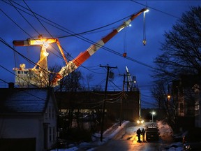 A giant crane dominates the skyline at dawn as shipyard workers make their way to Bath Iron Works on Jan. 4 in Maine.