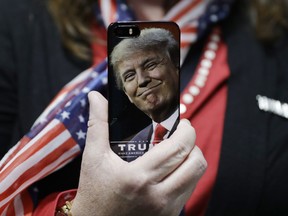 In this Thursday, Sept. 2016, file photo, a woman holds up her cell phone before a rally with then presidential candidate Donald Trump in Bedford, N.H. Trump's use of an old Android phone to tweet is causing security concerns.