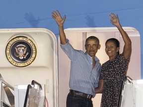 U.S. President Barack Obama and first lady Michelle Obama wave at people from Air Force One as they leave Joint Base Pearl Harbor-Hickam, adjacent to Honolulu, Hawaii, en route to Washington, Sunday, Jan. 1, 2017, after their annual family vacation on the island of Oahu — the last Obama will take a president. He now faces his last three weeks in office.