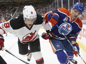 Taylor Hall, left, of the New Jersey Devils battles in the corner with Andrej Sekera of the Edmonton Oilers during NHL action Thursday night in Edmonton. Hall was making his first return to Edmonton since being traded by the Oilers after last season. The Oilers were 3-2 winners in overtime.