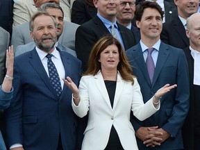Interim Conservative Leader Rona Ambrose, middle, is flanked by NDP Leader Tom Mulcair and Prime Minister Justin Trudeau as they join federal members of parliament, Senators and parliamentary staff pose for a photo to mark the 150th anniversary of Parliament on Parliament Hill in Ottawa on Wednesday, June 8, 2016.