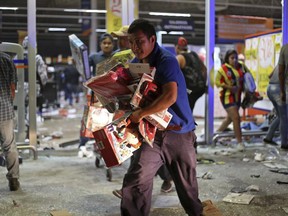 A man runs with toys as a store is ransacked by a crowd in the port of Veracruz, Mexico, Wednesday Jan. 4, 2017
