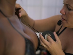 Erika Martins uses black electrical tape on Jan. 11, 2017, to create a customer's bikini on her rooftop Erika Bronze salon in the suburb of Realengo in Rio de Janeiro, Brazil.