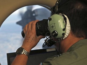 In this March 22, 2014, file photo, Flight Officer Jack Chen uses binoculars at an observers window during the search for the missing Malaysia Airlines Flight MH370