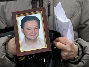 In this Monday, Nov. 30, 2009, file photo a portrait of lawyer Sergei Magnitsky who died in jail, is held by his mother Nataliya Magnitskaya, as she speaks during an interview with the AP in Moscow.
