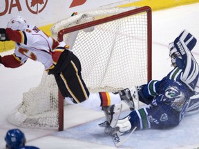Calgary Flames' Deryk Engelland trips over Vancouver Canucks' goaltender Ryan Miller during NHL action Friday night in Vancouver. Miller made 44 stops as the Canucks made it six straight victories with a 4-2 victory.