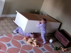 Bowdy Shoff, 2, pushes a toppled dresser off his twin brother Brock.