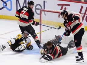 Ottawa Senators' goaltender Mike Condon loses his helmet as he comes out of his crease to smother a loose puck during NHL action Thursday in Ottawa. Lending assistance is Kyle Turris, left, and Erik Karlsson. Penguins' Scott Wilson is sprawled on the ice after crashing over Condon.