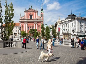 Tourists and residents walk across the Tromostovje bridge in Ljubljana, Slovenia.