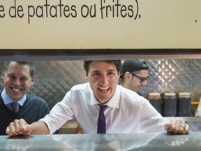 Prime Minister Justin Trudeau peers out from behind the counter at a smoked meat restaurant, Wednesday, January 18, 2017 in L'Ile-Perrot, Quebec