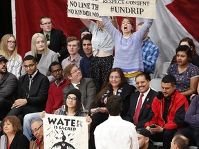 Prime Minister Justin Trudeau speaks with pipeline protestors as they stand and hold signs at a town hall at the University of Winnipeg in Winnipeg, Thursday, January 26, 2017.