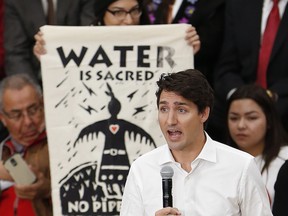 Prime Minister Justin Trudeau speaks with the public as a pipeline protestor stands behind him at a town hall at the University of Winnipeg in Winnipeg, Thursday, January 26, 2017.