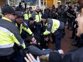 Police try to remove demonstrators from attempting to block people entering a security checkpoint, Friday, Jan. 20, 2017