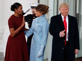 President-elect Donald Trump gives a thumbs-up as first lady Michelle Obama and Melania Trump talk at the White House in Washington, Friday, Jan. 20, 2017.