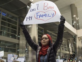 Demonstrators hold signs and chant in the baggage claim area during a protest against Trump, Sunday, Jan. 29, 2017, at Detroit Metropolitan Airport