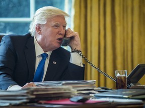 U.S. President Donald Trump speaks on the phone with Vladimir Putin, Russia's president, during the first official phone talks in the Oval Office of the White House in Washington, D.C., U.S., on Saturday, Jan. 28, 2017. Putin and Trump exchanged views on Russia-U.S. relations as Republicans in the U.S. Senate intensify calls to keep sanctions on Russia in place.